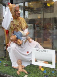 Optiker-Deko mit Papst, Babyklappe & Kondomen