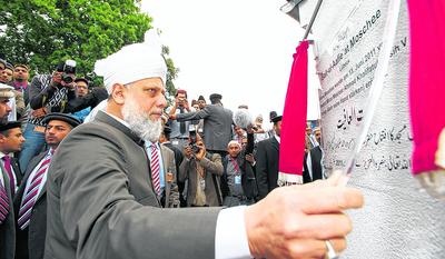 Der Kalif der Ahmadiyyas, Hazrat Mirza Masroor Ahmad aus London, eröffnet das muslimische Gotteshaus. An der Hauswand ist das traurige Datum der Landnahme auf einer Tafel notiert.