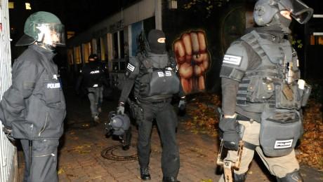 Elite-Polizisten verlassen mit Ramme, Schutzschild und Helm in der Hand die ehemalige Schule