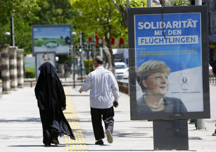 epa05273140 People walk next to a billboard with the picture of German Chancellor Angela Merkel with the words; 'Solidarity with the refugees', in Gaziantep, Turkey, 23 April 2016. German Chancellor Angela Merkel will visit refugee camps in Nizip district near Gaziantep on 23 April 2016. EPA/SEDAT SUNA