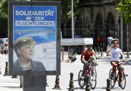 epa05273143 Young boys ride their bicycle next to a billboard with the picture of German Chancellor Angela Merkel with the words; 'Solidarity with the refugees', in Gaziantep, Turkey, 23 April 2016. German Chancellor Angela Merkel will visit refugee camps in Nizip district near Gaziantep on 23 April 2016. EPA/SEDAT SUNA