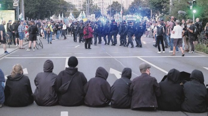 Leipzig am Montagabend: Eine dünne Kette nicht einmal besonders mutiger Antifas konnte sich seelenruhig auf der Straße niederlassen, geduldet von den Polizisten, die wiederum von jenen angewiesen wurden, denen genau dieses Bild in die Hände spielte. Leipzig am Montagabend: Eine dünne Kette nicht einmal besonders mutiger Antifas konnte sich seelenruhig auf der Straße niederlassen, geduldet von den Polizisten, die wiederum von jenen angewiesen wurden, denen genau dieses Bild in die Hände spielte.