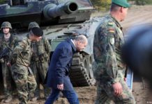 Bundeskanzler Olaf Scholz duckt sich vergangenen Oktober beim Vorübergehen an einem Kampfpanzer Leopard 2.