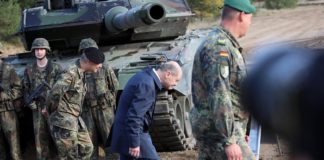 Bundeskanzler Olaf Scholz duckt sich vergangenen Oktober beim Vorübergehen an einem Kampfpanzer Leopard 2.