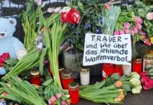 Inmitten der vielen Blumen vor dem Gebäude der Zeugen Jehovas in Hamburg-Alsterdorf liegt auch schon ein Transparent mit politischer Botschaft: „Trauer – und Wut über das fehlende Waffenverbot.“