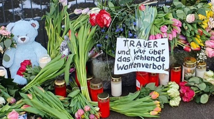 Inmitten der vielen Blumen vor dem Gebäude der Zeugen Jehovas in Hamburg-Alsterdorf liegt auch schon ein Transparent mit politischer Botschaft: „Trauer – und Wut über das fehlende Waffenverbot.“